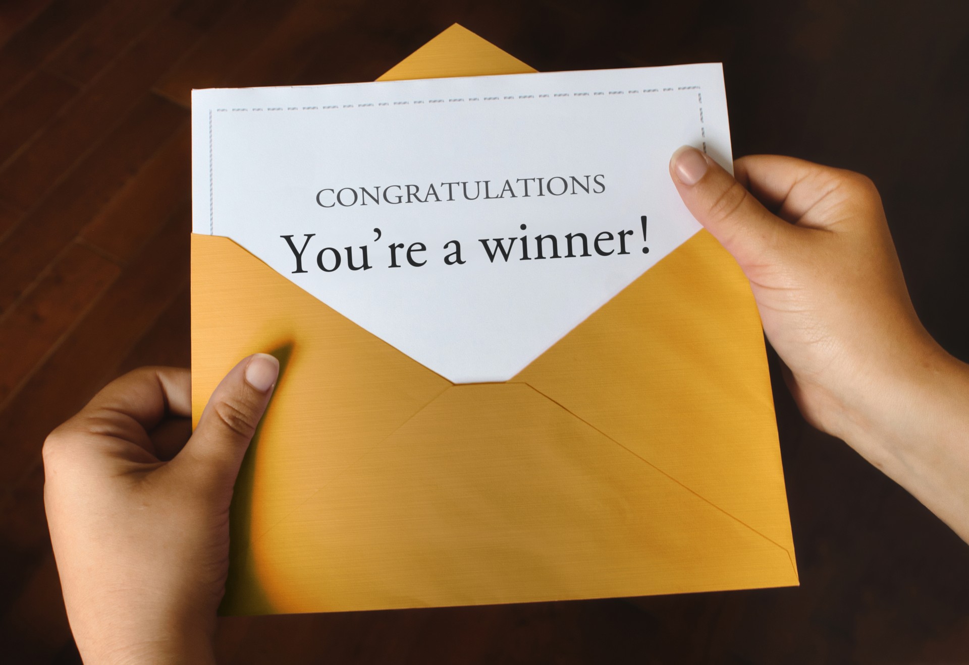 An open shiny gold envelope with a letter that says Congratulations You're a winner!